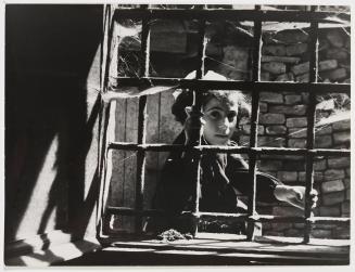 Girl gripping on window bars, Italy