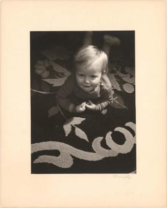 Portrait of toddler boy lying on a rug