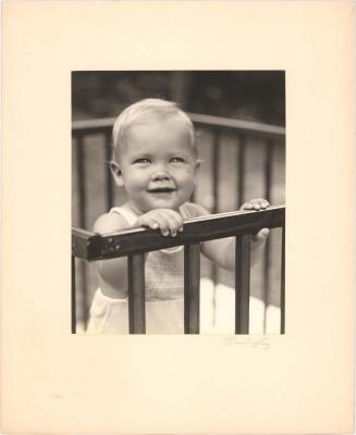 Portrait of baby standing up in a playpen